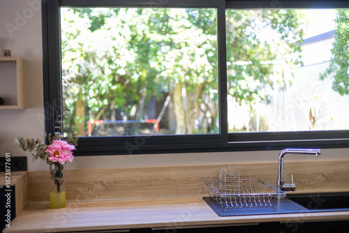 Une cuisine avec évier moderne avec des fenêtres, on voit une forêt depuis la cuisine, villa moderne