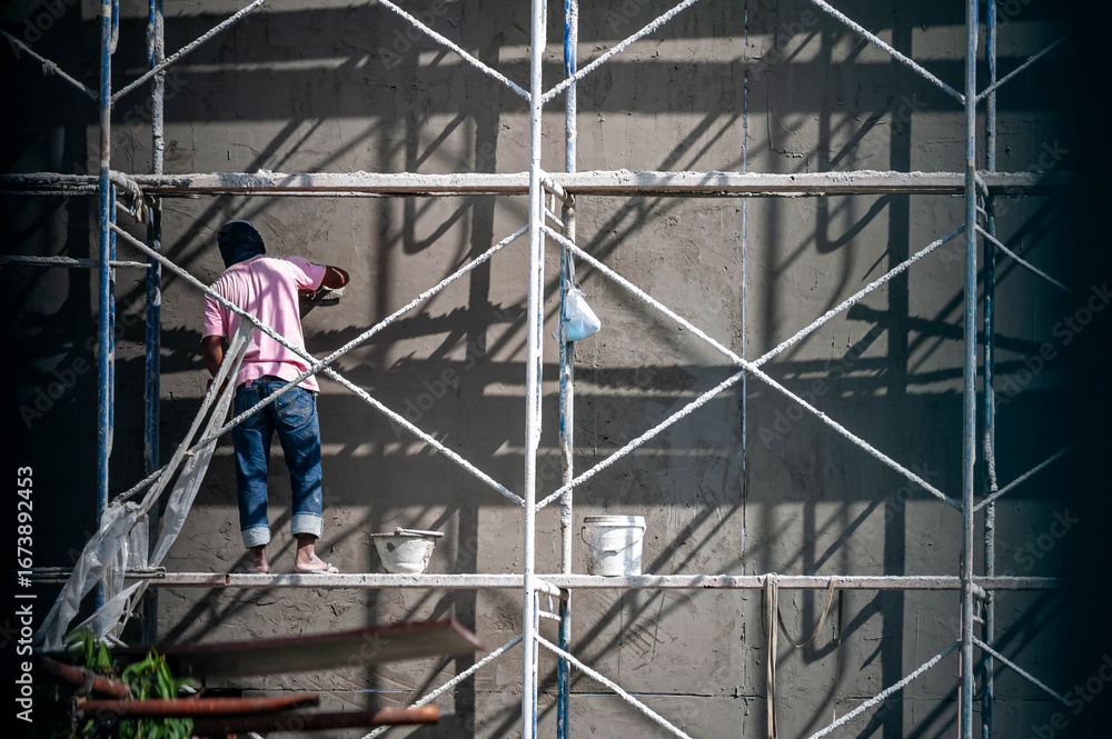 Fototapeta premium Worker on Scaffolding Painting Wall