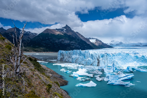 Panoramic view of the Perito Moreno Glacier in Patagonia, Argentina, with turquoise waters, icebergs, and dramatic mountains under a cloudy sky