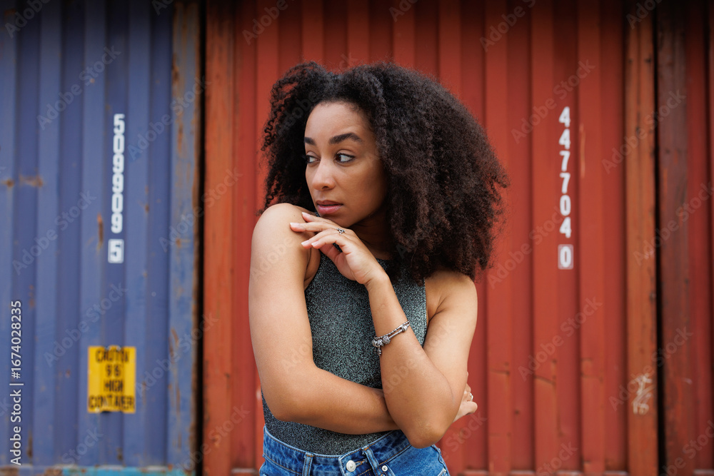 Fototapeta premium African american woman in bodysuit looking away near colorful cargo containers 