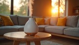 Modern ultrasonic essential oil diffuser emits steam on wooden table. Soft light from setting sun streams through windows illuminating grey sectional sofa with yellow pillows. Creates relaxing
