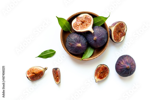 Fresh ripe figs with leaves on a wooden bowl top view on a white background