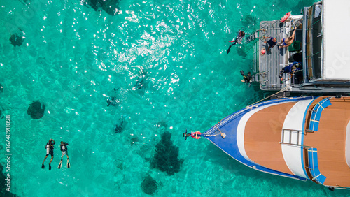 Obraz na płótnie Aerial view of scuba divers swimming on water surface and climbing up on boat pl