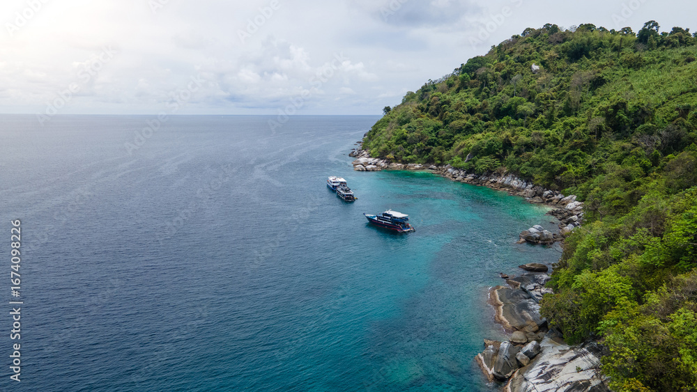 Fototapeta premium Group of recreational vessels or scuba diving boats anchoring over turquoise clear water at Racha Noi Island or Koh Racha Noi in Phuket, Thailand. Aerial view of a popular destination in Andaman sea