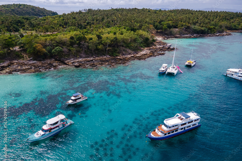 Obraz premium Aerial view of Koh Racha Yai Island with many tour boats, yacht, catamaran and longtail boat anchoring around the bay. A popular destination for summer vacation