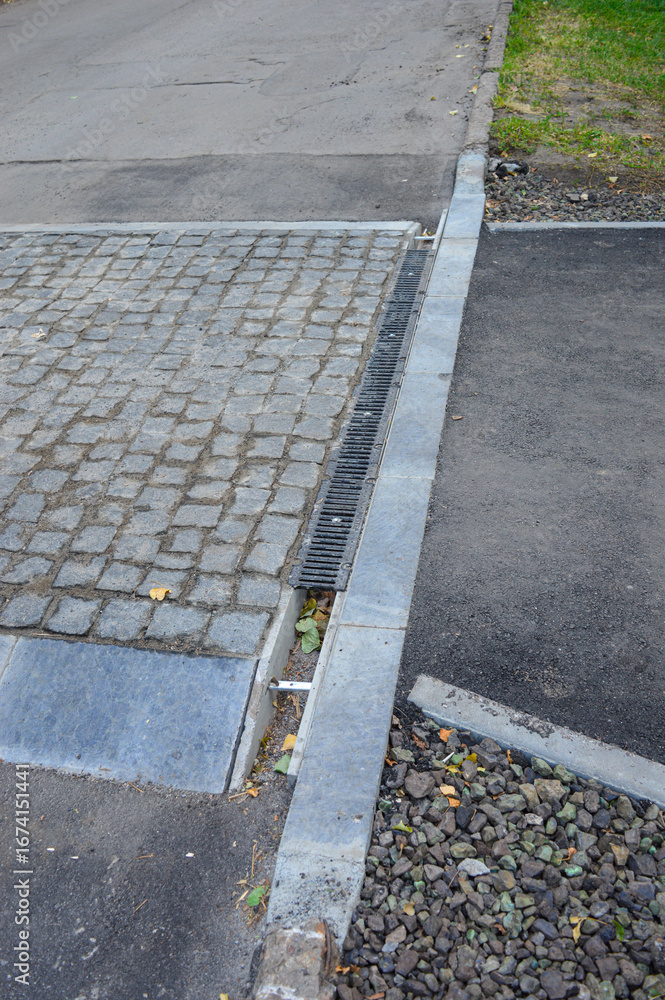 Fototapeta premium Overhead view of a transition between asphalt, stone pavement, and concrete curbing with a drainage channel. Concept for urban planning, road construction, and municipal infrastructure