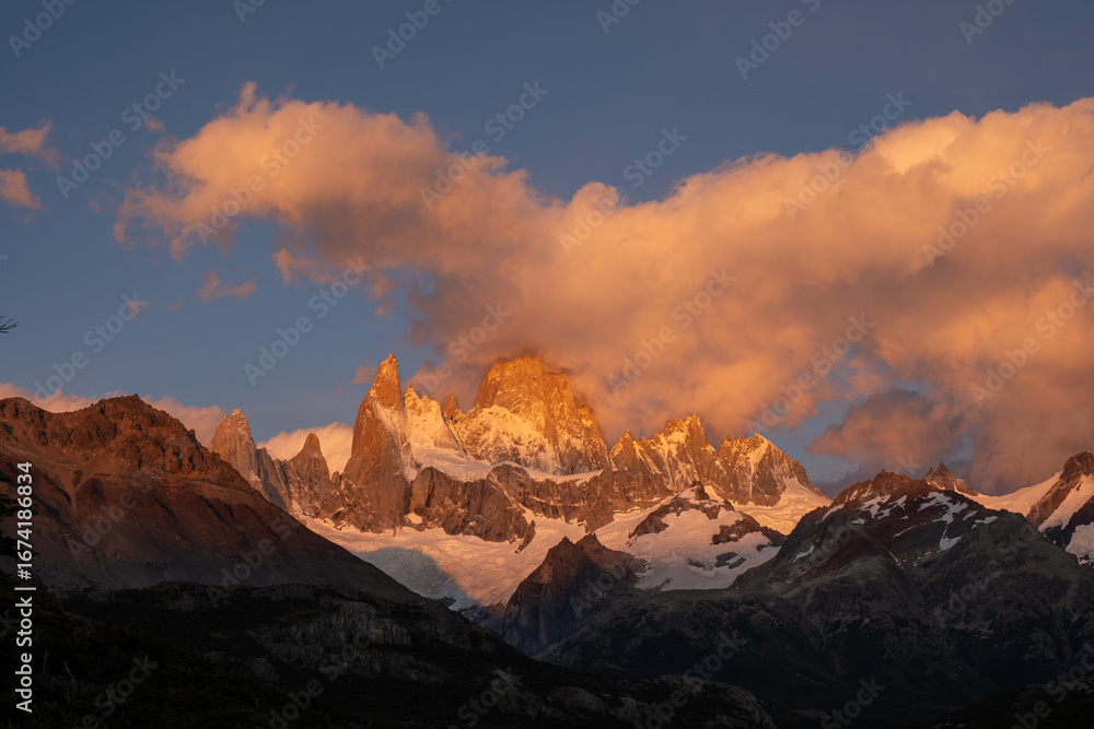 Obraz premium Magical sunrise on Mount Fitz Roy, Patagonia. The snow-capped mountains are bathed in golden light beneath vibrant clouds