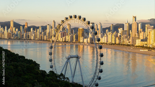 Golden hour view of Balneario Camboriu skyline with the FG Big Wheel ferris wheel at Barra Norte, Santa Catarina, Brazil.