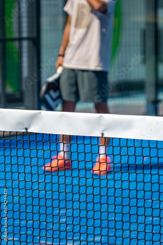 Padel player waiting behind the net on a blue paddle court