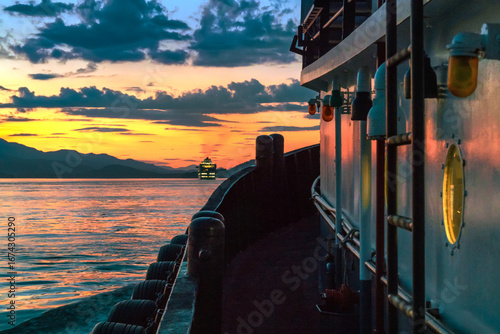 Tug boat traveling at twilight with cruise ship ahead.