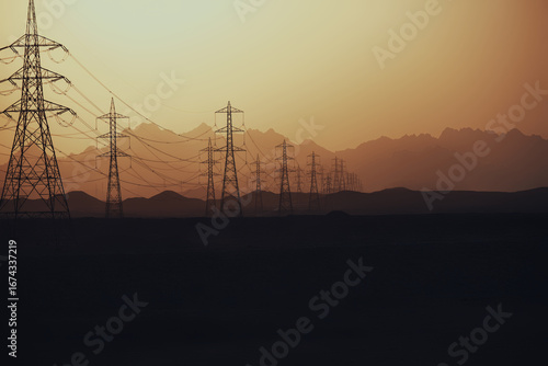 Power lines at sunset in the sandy desert against the background of mountain layers, Egypt.