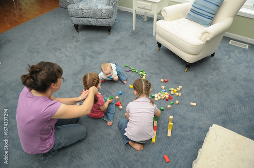 Girls Playing with Blocks While Mother Braids Hair in Living Room at Home
