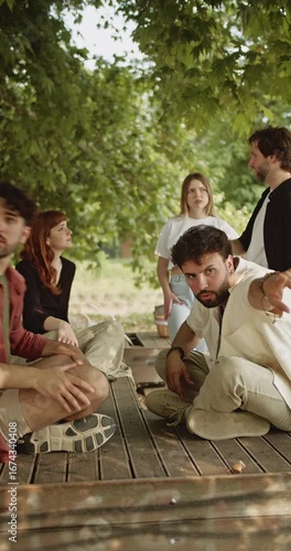 A group of happy young friends gathered in a vibrant green park, enjoying cheerful conversation and bonding on a wooden deck. Captures moments of outdoor leisure, friendship, and community connection.