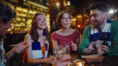 Happy buddies drinking beer in sport bar closeup. Smiling young people clinking 