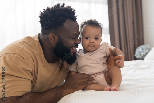 Happy time for African American family. African American father takes care and spends time with his newborn baby on bedroom at home.  Infant baby health care with love and kindness