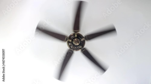 A ceiling fan spinning with visible motion blur on a white ceiling