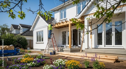 Construction Worker Building a Wooden Pergola on a Modern White House on a Sunny Day