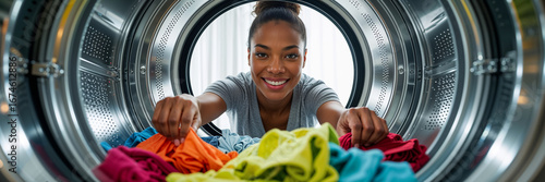 positive young woman putting things in washing machine drum
