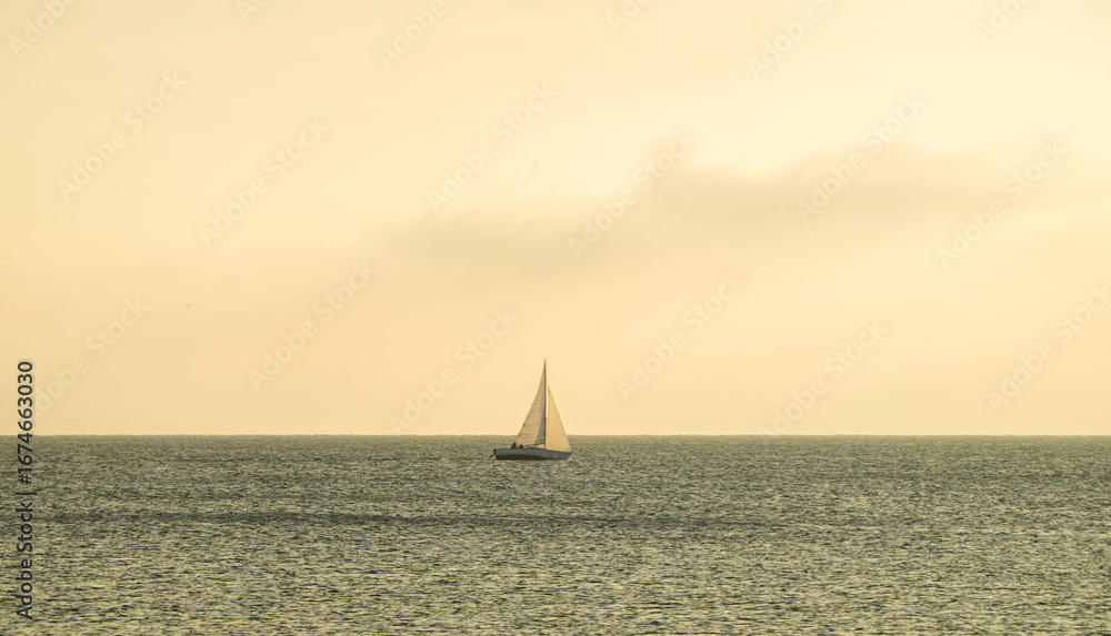 Fototapeta premium Sailboat on Lake Geneva at sunset with sun rays through clouds