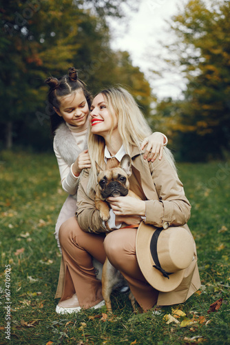 Mother and her daughter with a little puppy french bulldog in a park