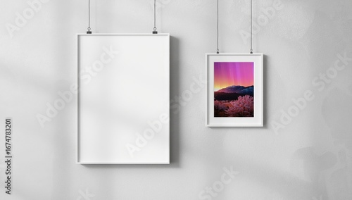Two framed pictures hanging on a textured concrete wall with natural light casting shadows creating a modern minimalist gallery display of art and photography