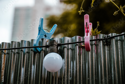 Colorful Clothespins and a Light Bulb on a Metal Fence