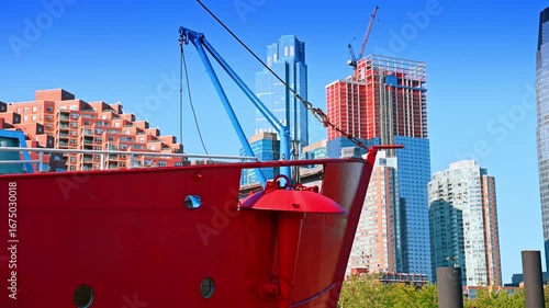 Old style boat with a red deck. Low angle view. Modern high-rises at backdrop. Jersey, USA.