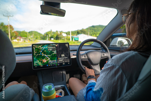 Tableau sur toile Woman drive modern EV car with GPS navigator travel in nature village