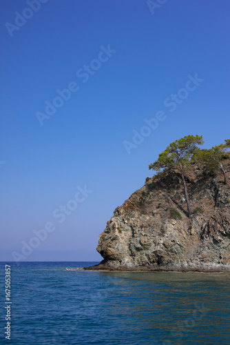 Rocky land in the sea on sunny day and blue sky. Blue water and bright summer view.