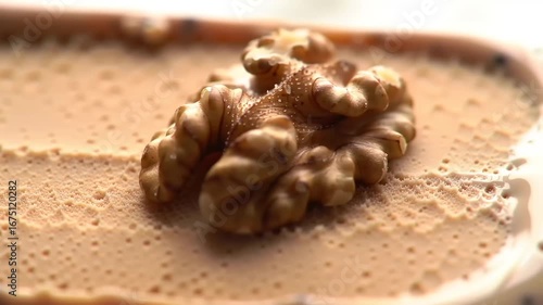 Walnut on a light brown ice cream closeup