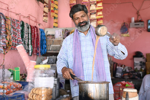 Obraz na plátně Indian tea seller enjoying preparing delicious yummy tea in happy mood for his clients at his tea-stall