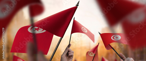 Tunisia flags in their hands on a blurred urban background