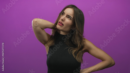 Obraz na plátně Woman holding neck in studio against vibrant purple backdrop with eyes closed in apparent pain and tense expression; discomfort