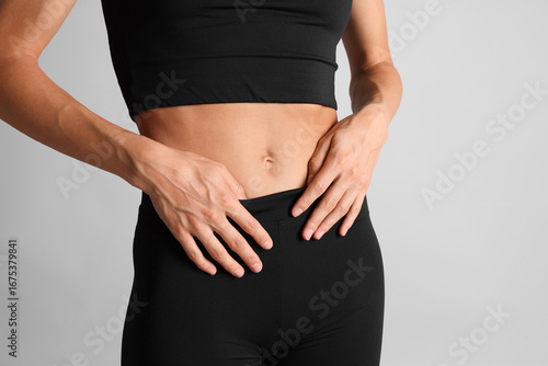 Woman with flat belly on light grey background, closeup