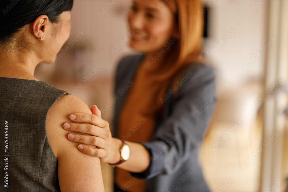 Fototapeta premium Businesswoman offering comfort and support to her colleague by touching her shoulder during office meeting