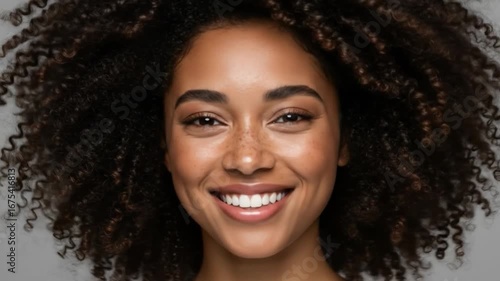 Radiant smile of a young woman with curly hair beauty portrait isolated on neutral background