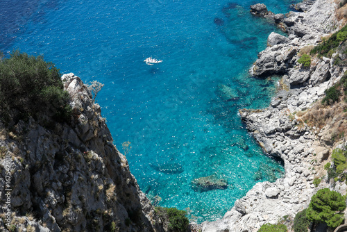 A place of turquoise waters and rocks, with a small group of canoeists, on the island of Capri in Naples, on a clear and sunny summer day