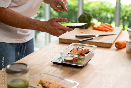 Fotografija Person using smartphone app for calorie counting and photo sharing above homemade weight loss meal prep