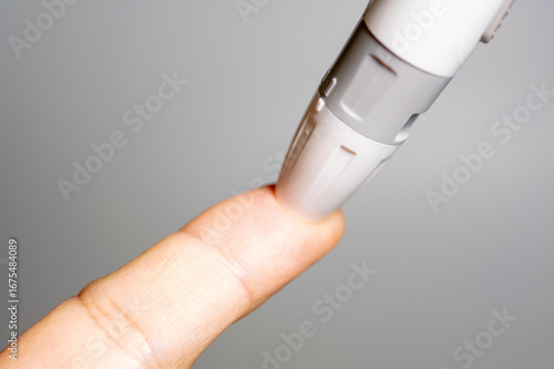Картината върху платно A close-up of a lancet device poised to prick a person's fingertip for a blood sample