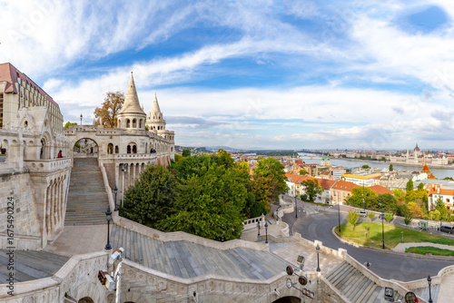 Foto Wide panorama of Fisherman's Bastion with conical towers, arcades, and grand staircase leading to Danube, featuring Parliament building view under autumn sky