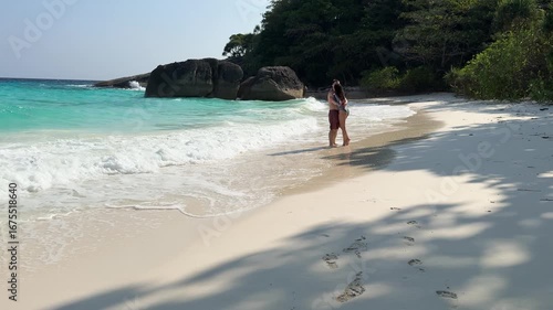Romantic couple embracing and kissing by turquoise sea on sandy beach in tropical paradise, Similan Islands.