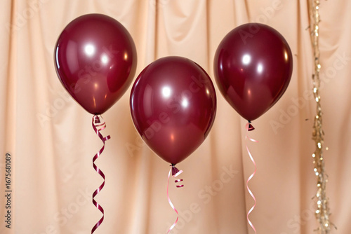Three Deep Red Balloons with Curly Ribbons Against a Soft Fabric Background party celebration
