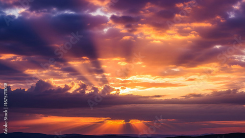 A stunning high-definition photograph of a dramatic sunset or sunrise. The sky is a canvas of deep purples, fiery oranges, and soft pinks.