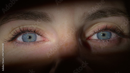 Bilde på lerret Woman opening her beautiful blue eyes, looking at the camera smiling, while the light illuminated her upper and midface area, close up shot