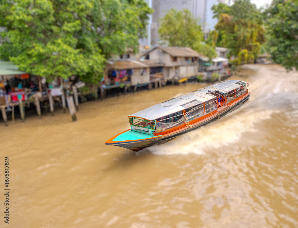 Obraz premium Ferry boat going through a Canal Khlong in Thai running from Soi 15 Sukhumvit Rd NANA to Siam and Platunam in BKK Bangkok Thailand