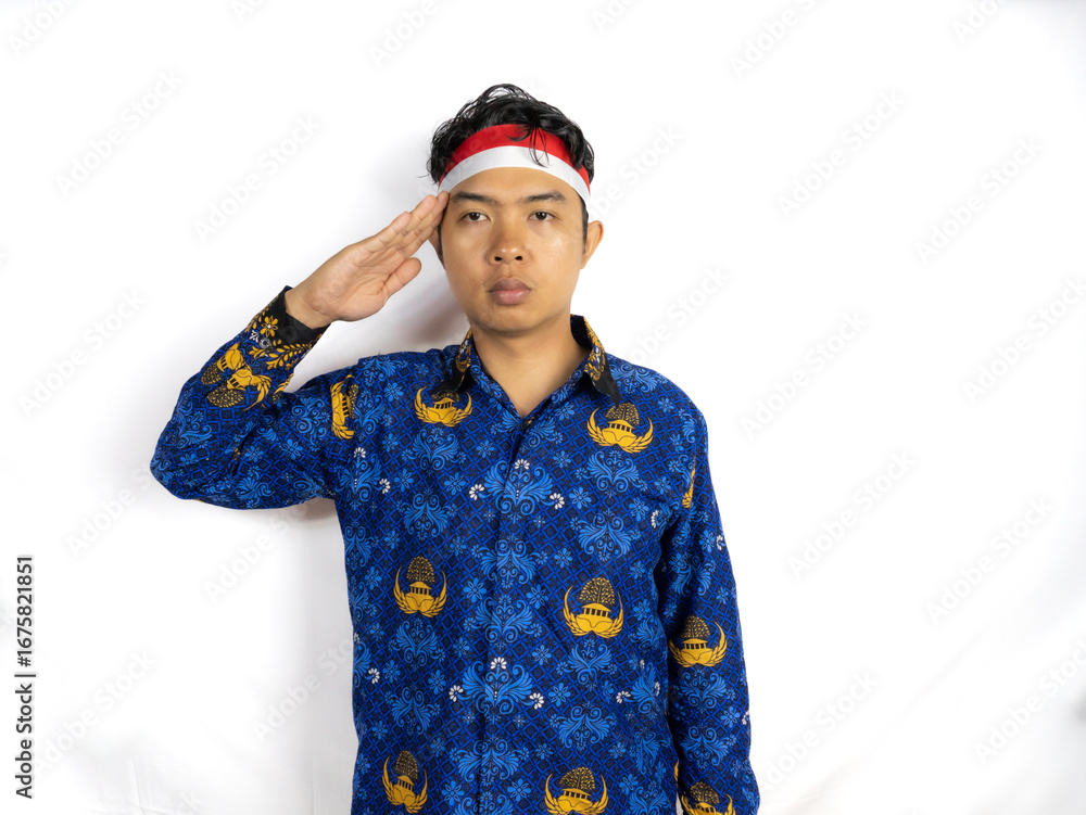 Fototapeta premium A young man Asian government worker with a happy successful expression, wearing flag headband and korpri uniform isolated by white background. Indonesia's independence day concept.