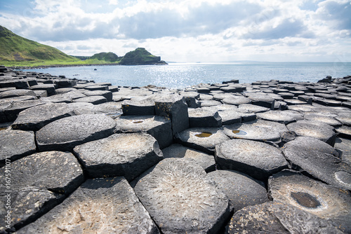 Hexagonal basalt columns at Giants Causeway Northern Ireland with sunburst sky evoking the legend of a giants causeway between Ireland and Scotland