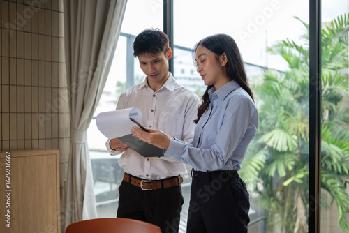 Male and female colleagues discussing project details while analyzing paperwork in a bright workplace. Free Download Male and female colleagues discussing project details while analyzing paperwork in a bright workplace. - GFXLoad