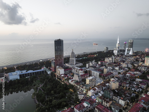Aerial view of the sun setting over the Black Sea, casting a soft glow on the skyline with the Alphabetic Tower and Batumi Tower standing tall, Batumi, Adjara, Georgia.