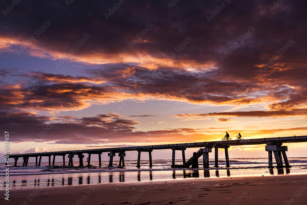 Obraz premium Butwani bridge and Malindi Pier area is a popular waterfront location known for stunning sunrises over the Indian Ocean. The pier is a concrete jetty that stretches about 400 meters into the ocean and